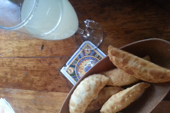 Snacking on fried cheese empanadas alongside a pisco sour.